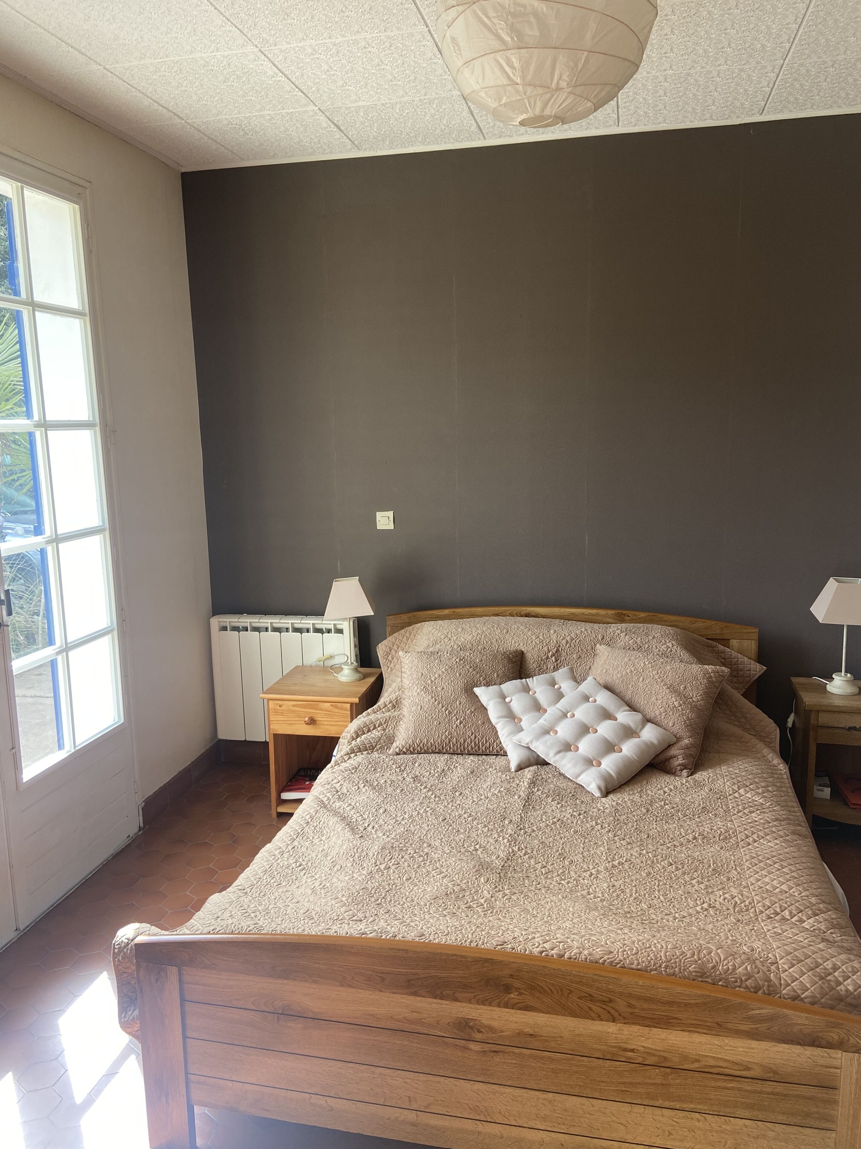 A bedroom with a large bed, wooden headboard, and a window with blinds.