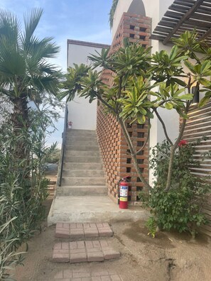 A staircase leading to a building with a brick wall and a fire extinguisher on the ground. - Hotel So Far So Good (El Pescadero)