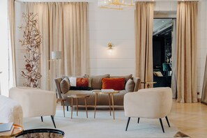 Una sala de estar moderna con un sofá, dos sillones, una mesa de centro y una lámpara de pie.