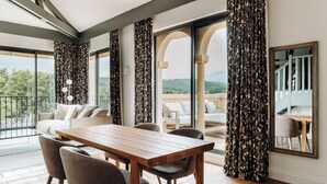 Un comedor moderno con una mesa y sillas de madera, ventanas amplias con cortinas y vistas al exterior.