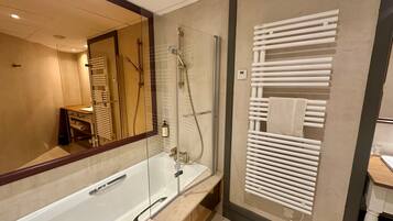 A modern bathroom with a glass-enclosed shower, a large mirror, and a towel rack.
