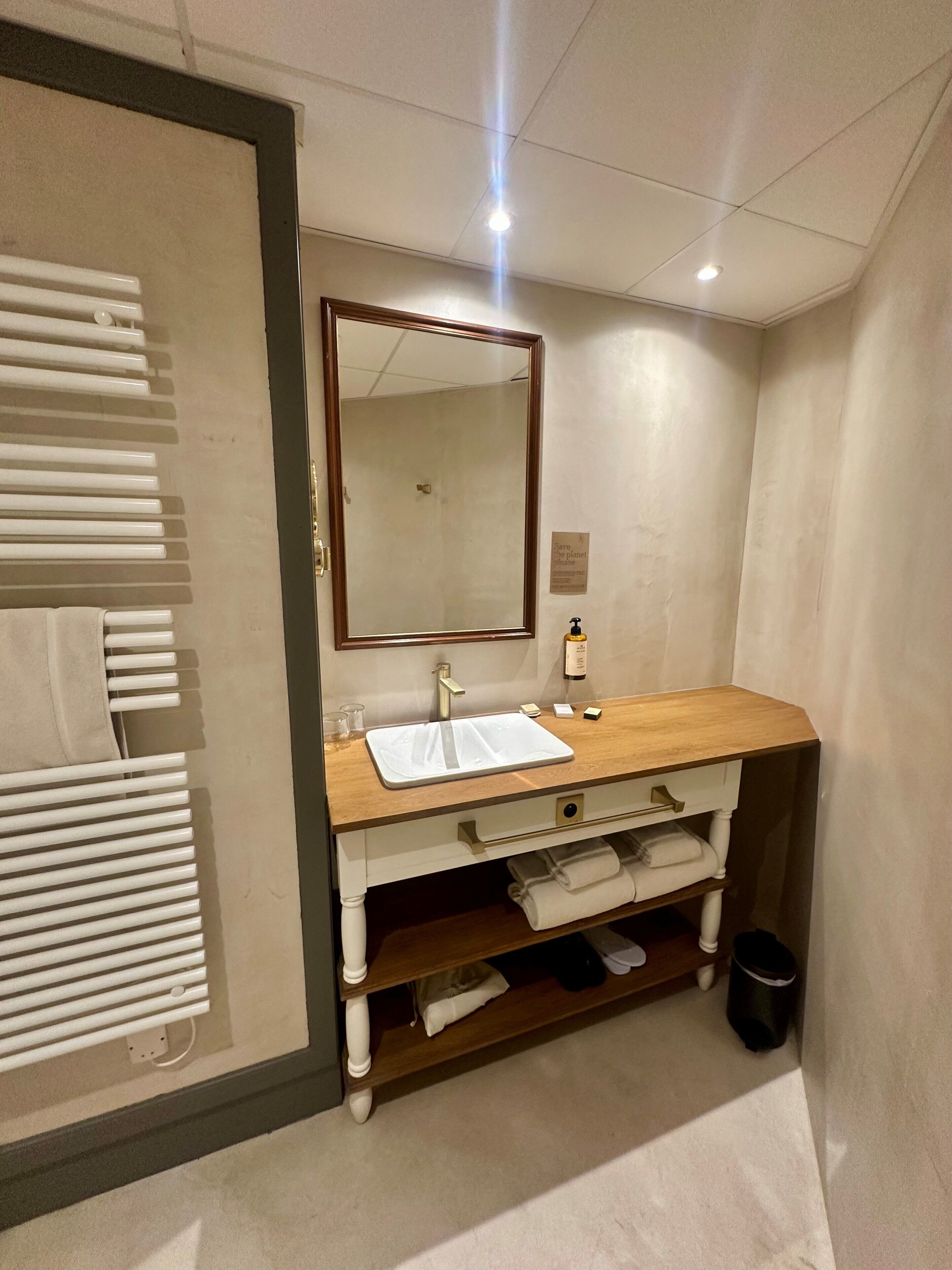 A bathroom with a wooden vanity, a mirror, a sink, and a towel rack.
