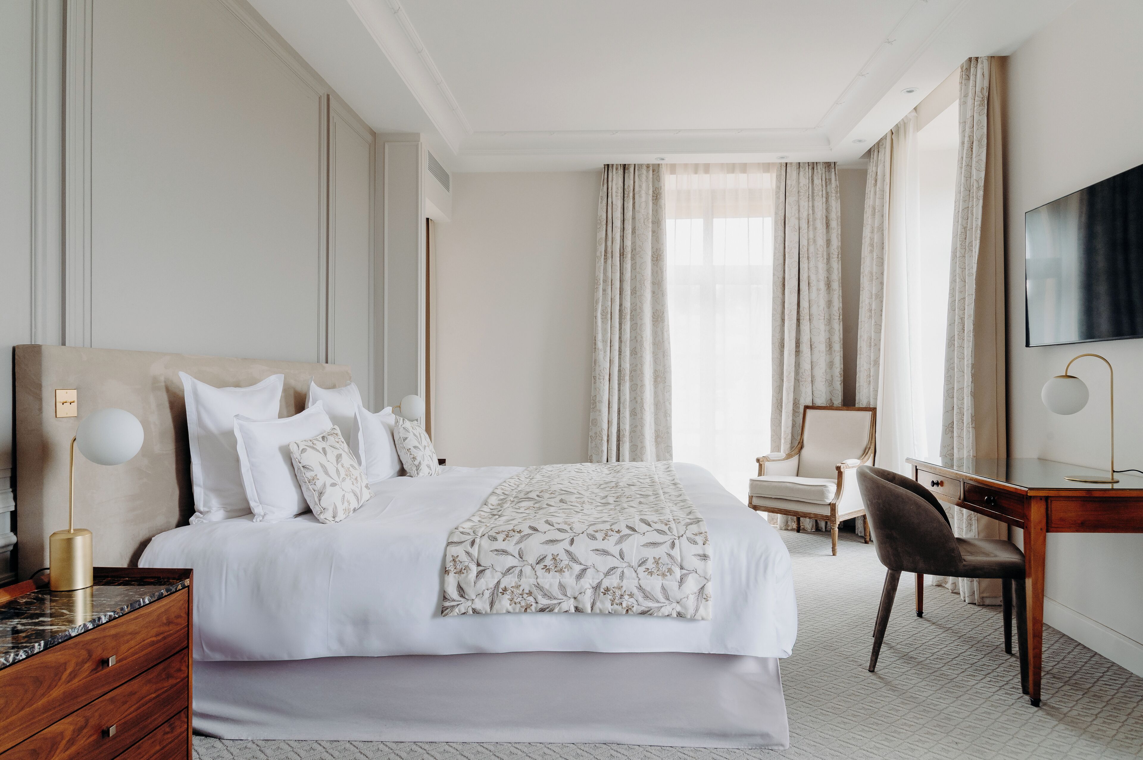 Habitación de hotel con una cama grande, un escritorio, una silla y un televisor.