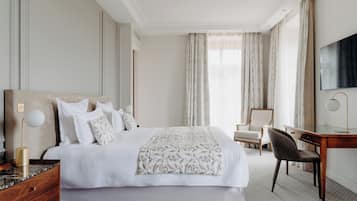 Habitación de hotel con una cama grande, un escritorio, una silla y un televisor.