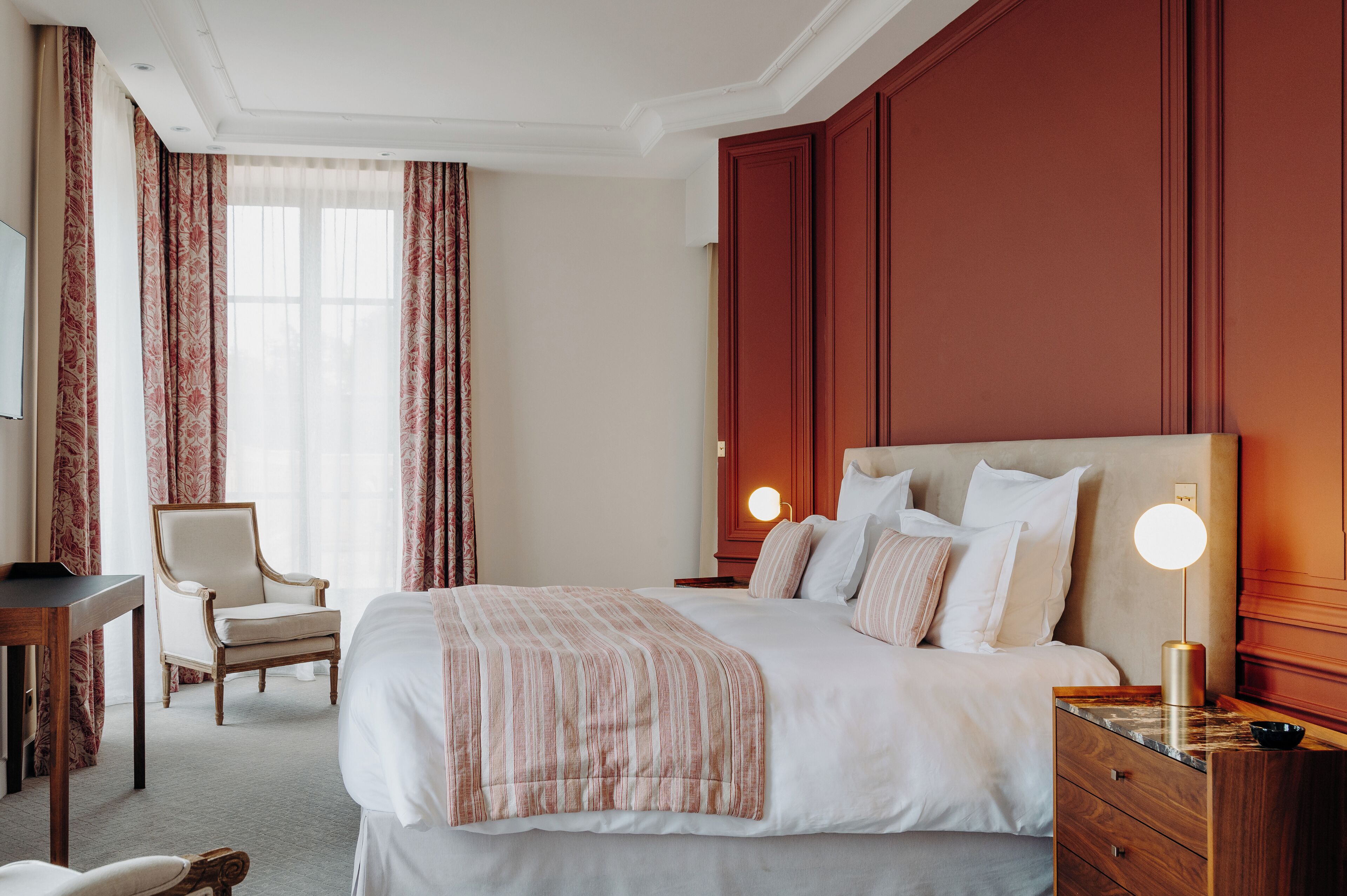 Une chambre d’hôtel avec un grand lit, un bureau, une chaise et une table de chevet avec une lampe.