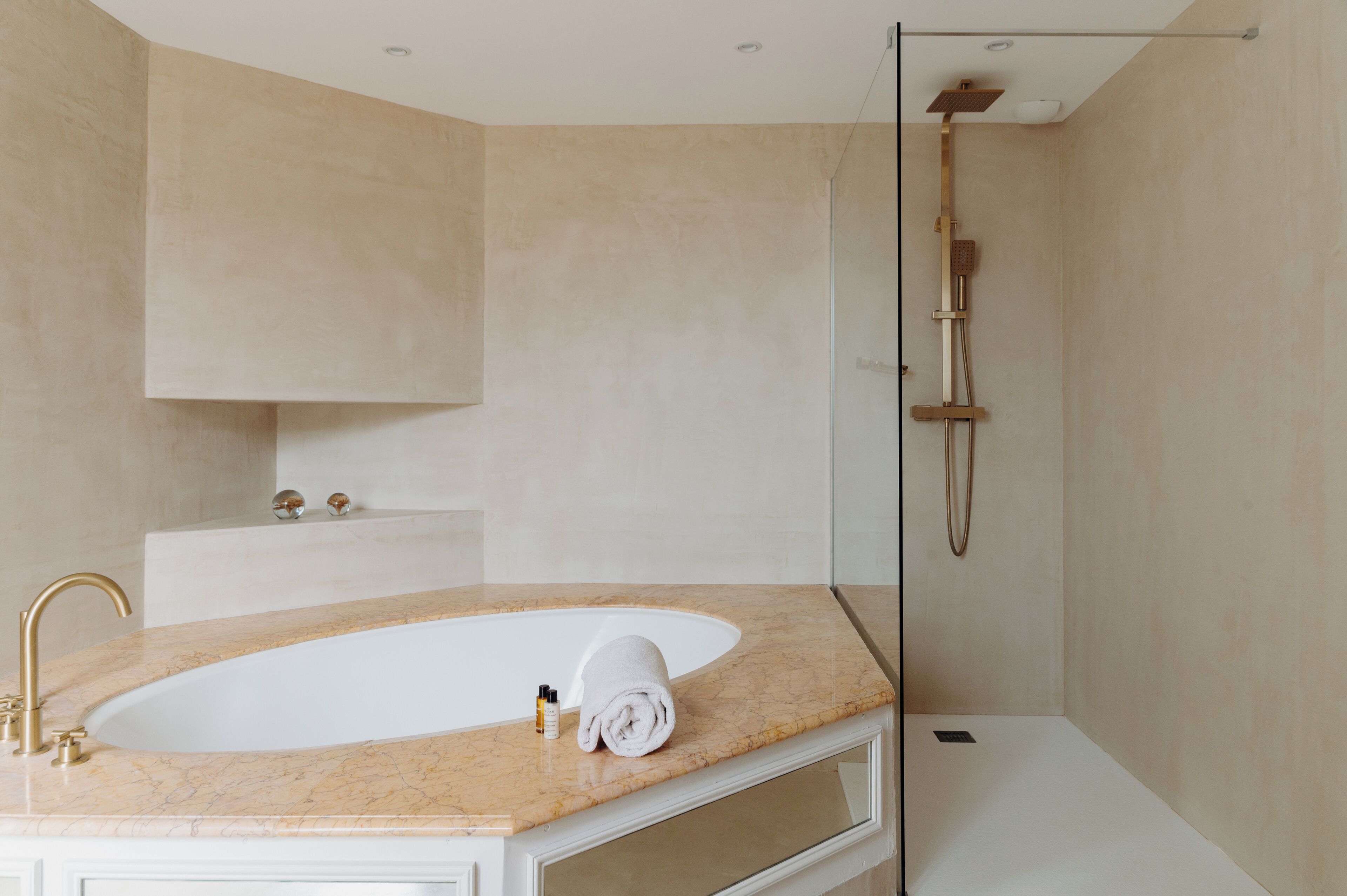 Un baño moderno con una bañera independiente, ducha con mampara de vidrio y encimera de mármol.