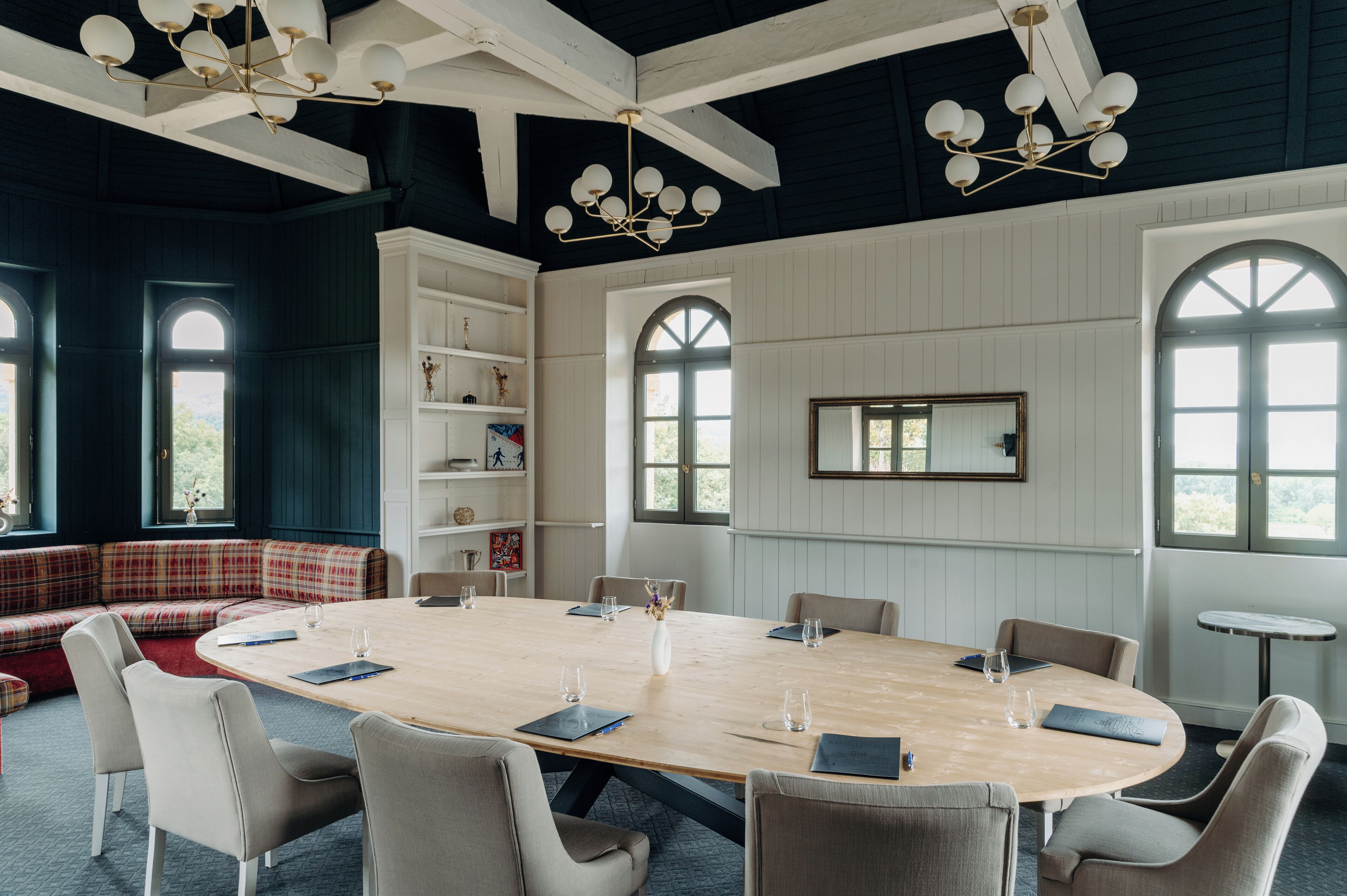 Une salle de conférence dotée d’une grande table en bois, de sièges confortables et d’un lustre moderne.