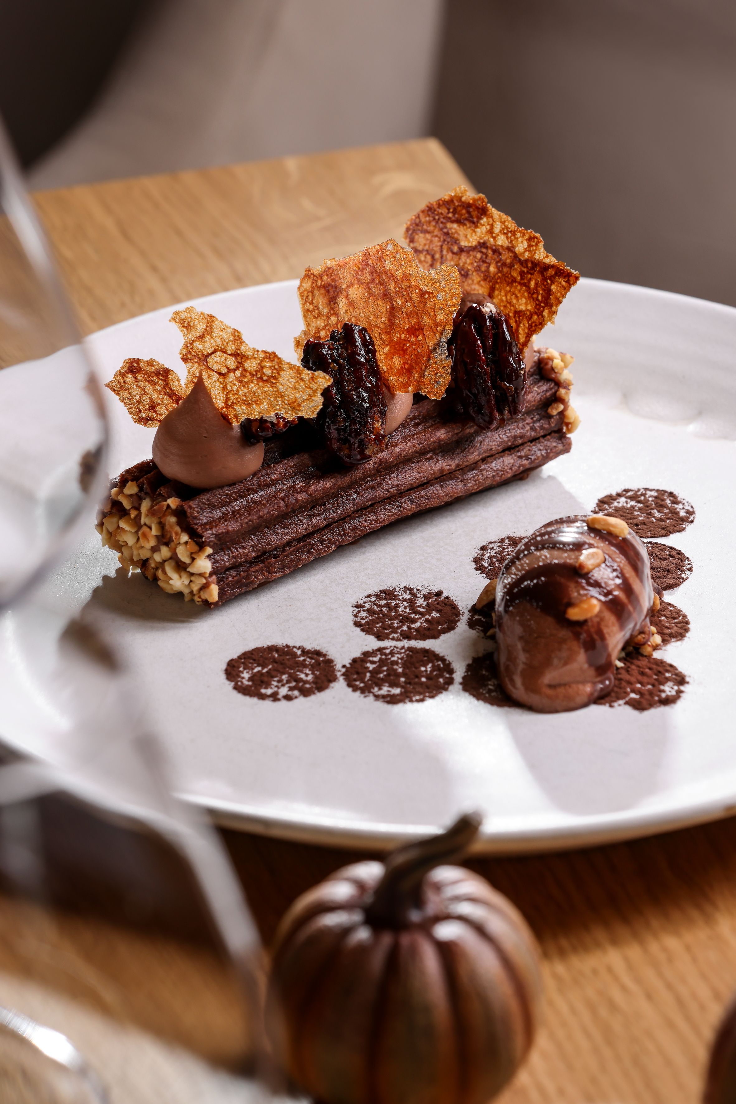Une assiette de dessert avec un dessert au chocolat, des noix et une sauce au chocolat.