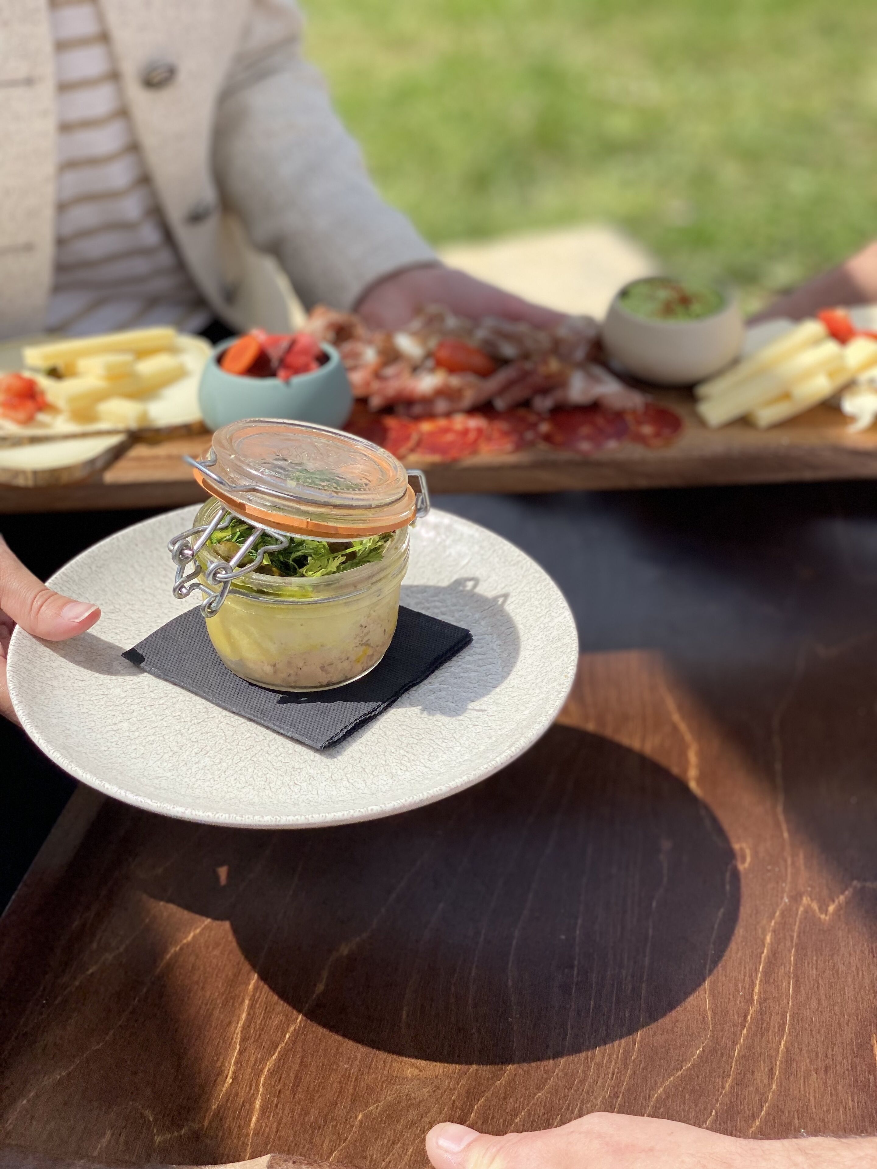 Una persona sosteniendo un frasco con verduras encurtidas sobre un plato.