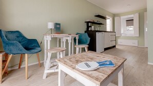 Een moderne keuken met witte kastjes, een zwart aanrecht en een blauwe stoel.