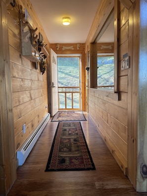 Enter a serene hallway leading to a breathtaking outdoor view through a large glass door.