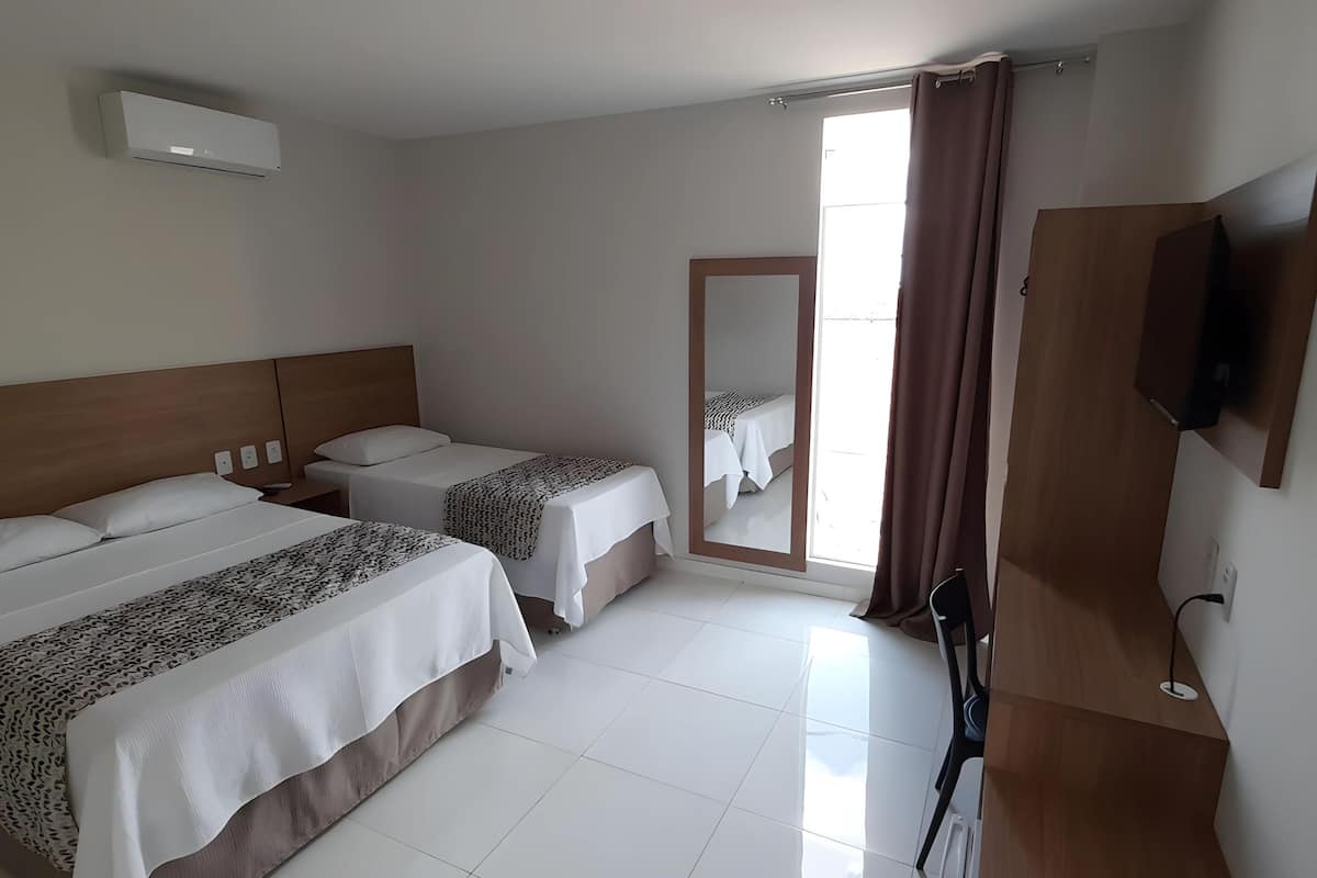 A hotel room with two beds, a TV, and a window with curtains.