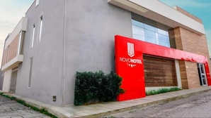 Un hôtel moderne, reconnaissable à son grand panneau rouge portant l’inscription NOVOHOTEL.