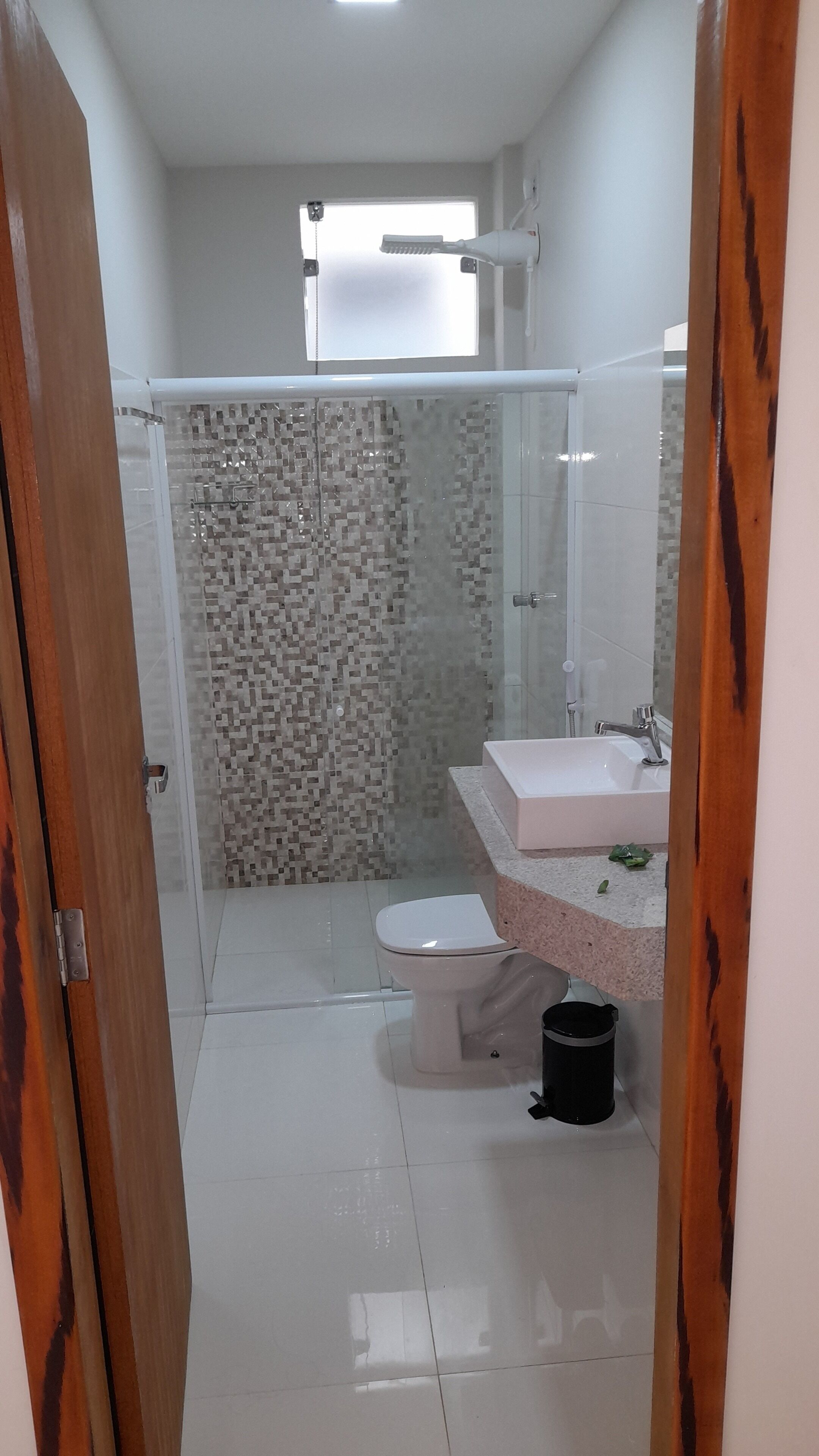 Een moderne badkamer met douche, toilet en wastafel.