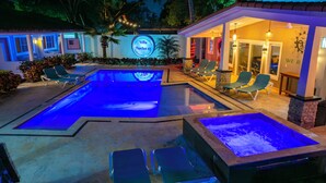 Un área de piscina con sillas de descanso, un letrero que dice "Villa Twelve 27" y una estructura de piedra.