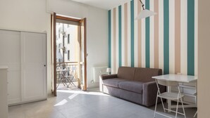 A room with a sofa, a table, a chair, a radiator, a door, and a window. - Hostmate - Milano - Botticelli - Città Studi  (Milano)