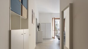 A hallway with a wardrobe, a small refrigerator, and a door leading to a balcony. - Hostmate - Milano - Botticelli - Città Studi  (Milano)