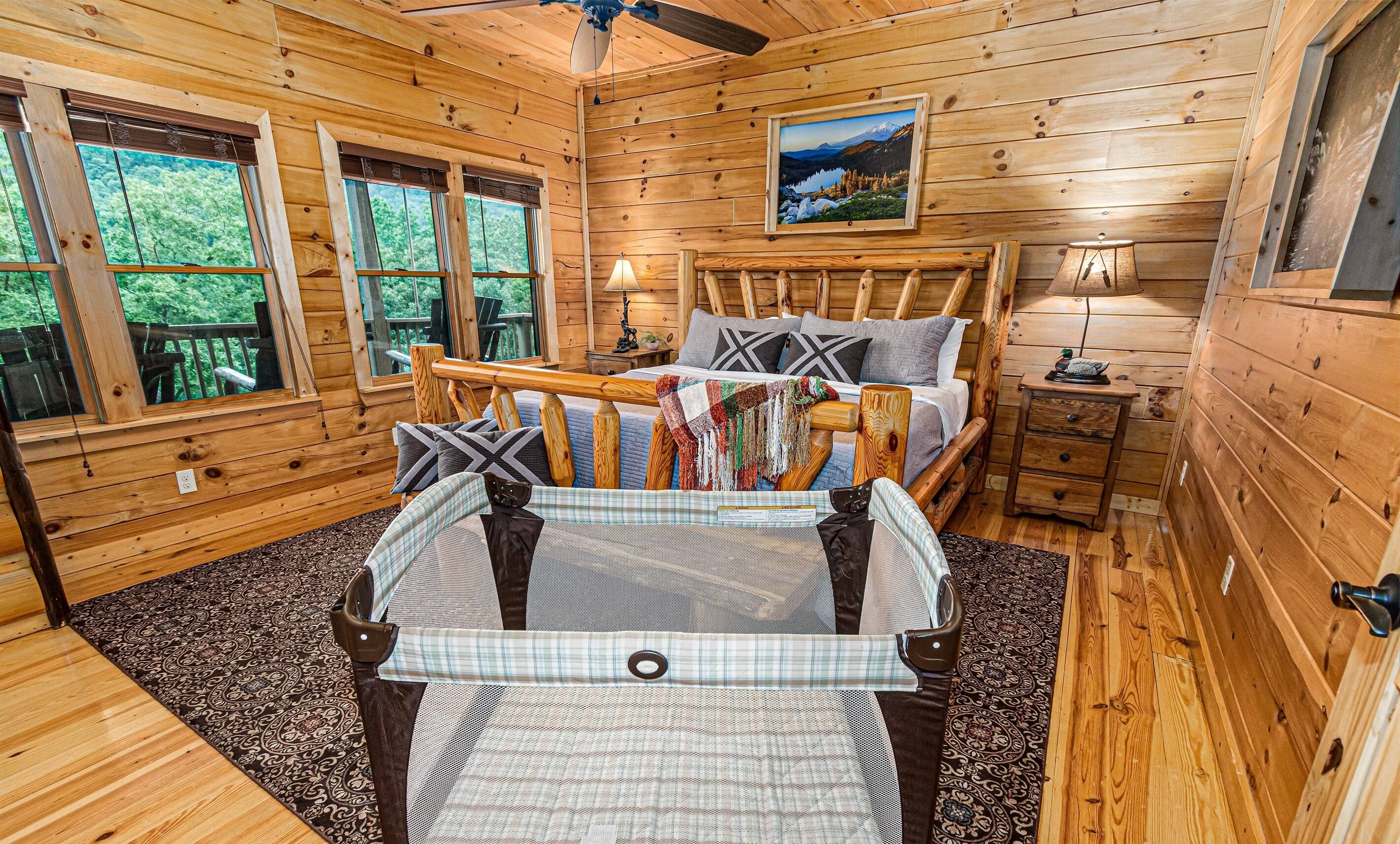 A wooden cabin bedroom with a bed, a nightstand, a window, and a painting on the wall.