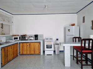 A compact kitchen with a microwave, toaster, coffee maker, and a small oven. There are wooden cabinets and a white countertop.