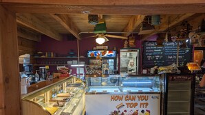 Une boutique de desserts avec une vitrine réfrigérée remplie de différentes sortes de glaces et une pancarte sur laquelle on peut lire : « COMMENT POURRAIT-ON FAIRE MIEUX ? ».