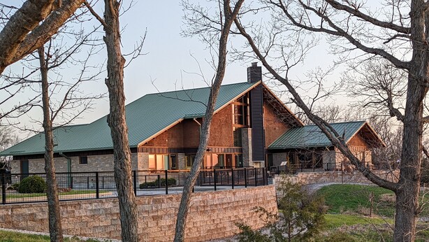 Un chalet à l’extérieur en pierre, doté de grandes fenêtres et d  ’un toit végétalisé.
