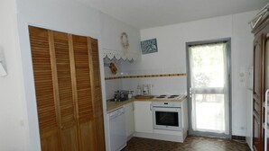 Uma cozinha compacta com forno embutido, cafeteira e armário de madeira.
