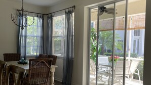 A dining area with a table and chairs, a chandelier, and a view through a sliding glass door to an outdoor patio. - Beautifully updated, gated community, minutes from the gulf beaches (Bonita Springs)