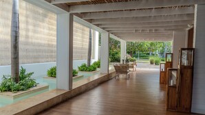A covered outdoor area with wooden flooring, a bench, and a small table with a vase.