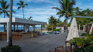 A wooden deck with a bar area, outdoor seating, and umbrellas.