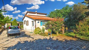 A house with a tiled roof, a paved driveway, and a garden with potted plants. - Holiday home mit Klimaanlage und Terrasse (Pula)