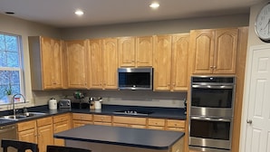 A kitchen with wooden cabinets, a built-in microwave, a double oven, and a dining table with chairs. - Stunning, spacious family home, adjacent to DT Annapolis, (Arnold)