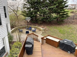 Eine Terrasse mit Sitzgelegenheiten im Freien, einem Basketballkorb und einem überdachten Grillbereich.