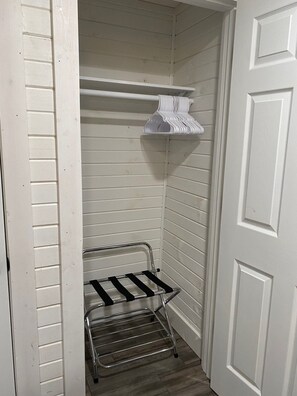Un armario pequeño, blanco, con un estante metálico y una puerta blanca.
