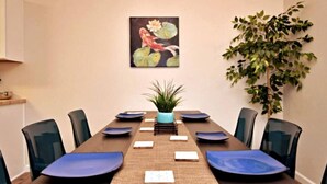 A conference room with a long table, chairs, a plant, and a painting on the wall. - Cozy Spacious Corporate Housing 4 BR|2.5 Bath|Loft|Office|Near Tesla (Austin)