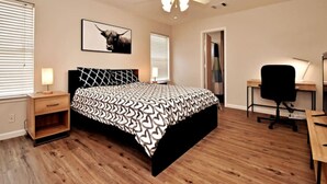 A bedroom with a bed, a desk, a chair, a ceiling fan, and a picture on the wall. - Cozy Spacious Corporate Housing 4 BR|2.5 Bath|Loft|Office|Near Tesla (Austin)