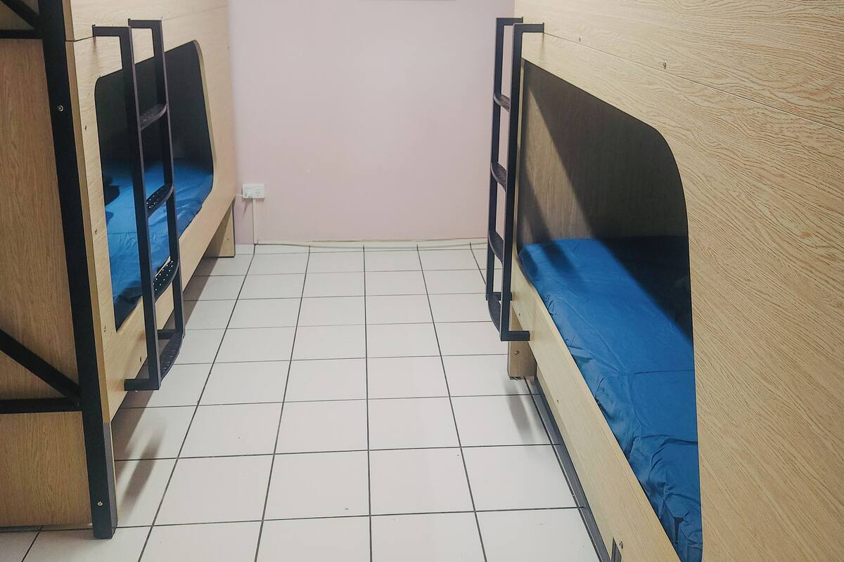 Una habitación con literas, suelo de baldosas y un cuadro en la pared.