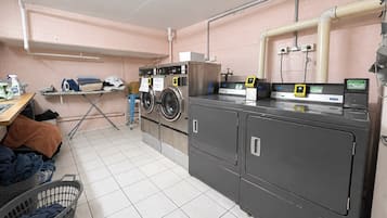A laundry room with washing machines, a drying rack, and a water meter.
