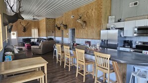 A rustic interior with a wooden dining area, a kitchen with modern appliances, and mounted deer heads on the walls. - 331 Acres of Comfort & Rest, ❤ of the Bluegrass- 12 mins from ARK w/Hot Tub  (Corinth)