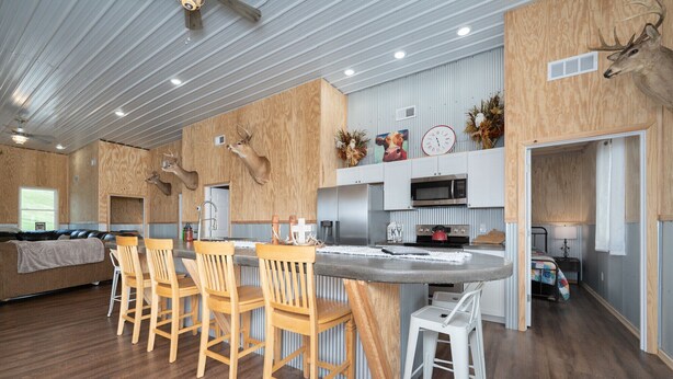 A modern kitchen with a central island, bar stools, and a seating area with a sofa and chairs. - 331 Acres of Comfort & Rest, ❤ of the Bluegrass- 12 mins from ARK w/Hot Tub  (Corinth)