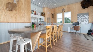 A kitchen with wooden cabinets, a bar area with stools, and a mounted deer head on the wall. - 331 Acres of Comfort & Rest, ❤ of the Bluegrass- 12 mins from ARK w/Hot Tub  (Corinth)