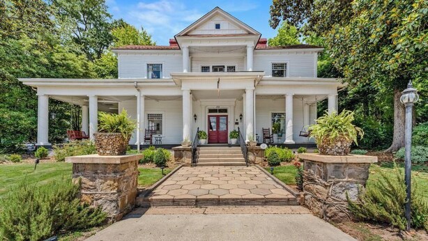 A two-story house with a central entrance, flanked by columns, and a red door. - The Veranda Historic Inn (Senoia)
