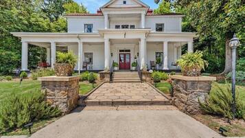 Stately two-story house with a central entrance and beautifully manicured garden.