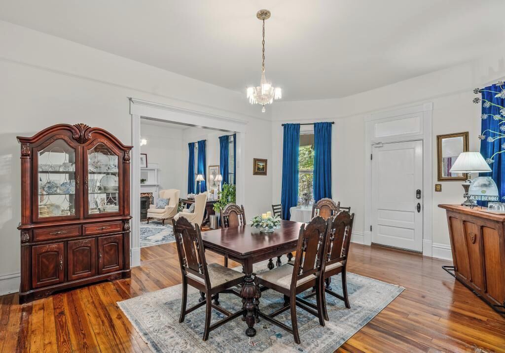 Une salle à manger avec une table et des chaises en bois, un lustre et un buffet aux portes vitrées.
