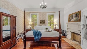 A four-poster bed with a wooden frame, two bedside tables with lamps, a fireplace, and a large mirror. - The Veranda Historic Inn (Senoia)