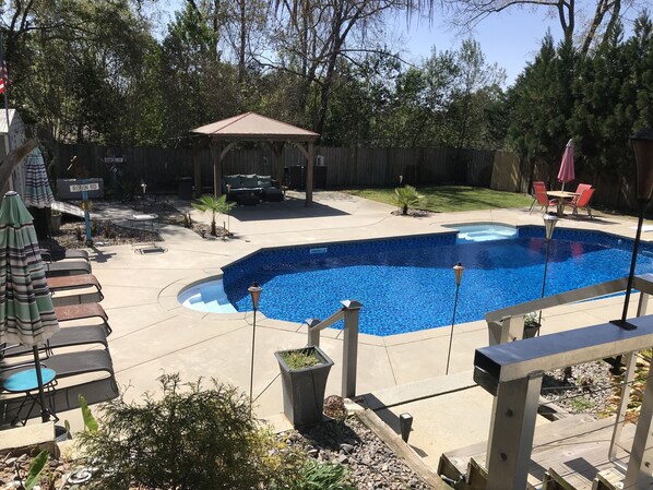 Un jardin avec une piscine, des meubles de patio et un belvédère.