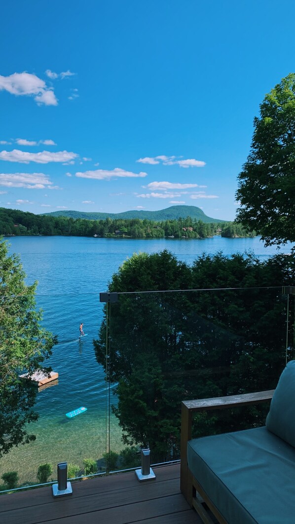 A deck with a view of a lake, surrounded by trees.