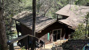 A wooden cabin with a stone staircase leading up to a wooden deck.