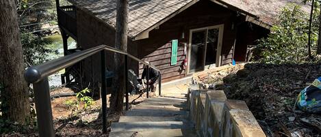 A wooden cabin with a stone staircase leading up to a wooden deck.