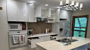 A modern kitchen with white cabinetry, a built-in oven, a coffee machine, and a large island with a sink.