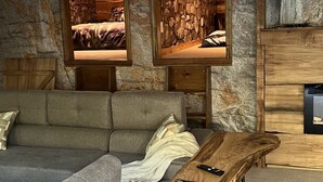 A modern living room with a stone wall, a sofa, a coffee table, and a wooden cabinet.